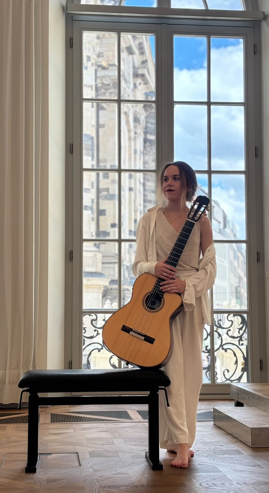Margaréta Lakner with her guitar by a window in Dresden